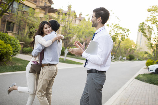 Happy young couple receiving house key from real estate agent