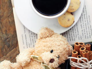 Overhead shot, teddy bear, coffee in white cup and saucer with shortbread and cinnamon
