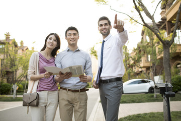 Happy young couple talking with confident businessman