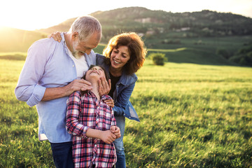 Senior couple with granddaughter standing outside in spring nature. Copy space.