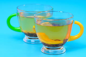 Hot spicy lemon tea in two stylish glass cups over a turquoise blue background