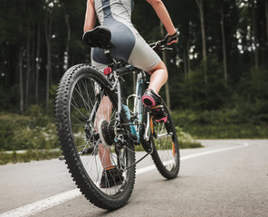 Fototapeta na wymiar Young Woman Riding on Mountain Bicycle near Forest