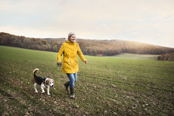 Senior woman with dog on a walk in an autumn nature.