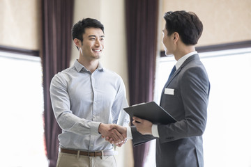Happy young man shaking hands with realtor