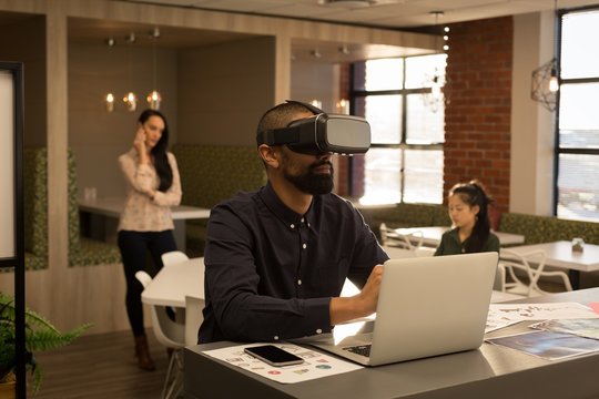 Male executive using virtual reality headset while working on