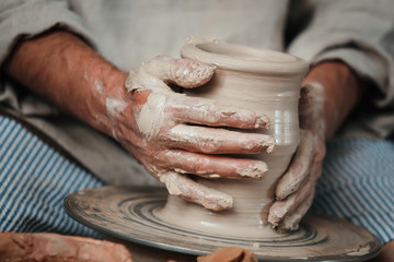 hands of a potter, creating an earthen jar on the circle 