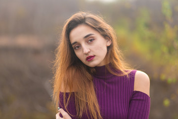 Fototapeta premium Girl in lilac dress on nature in autumn, Portrait of a beautiful girl in the autumn in the forest