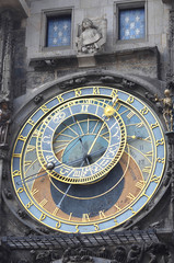 Details of Prague's Astronomical Clock. A statue is above the clock, between two blue windows with white stars.