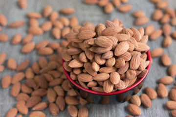 Pile of almonds nut in a black bowl against wooden background select focus shallow depth of field