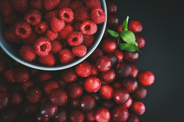 Raspberries and plums on a black table. Berries and fruit. 