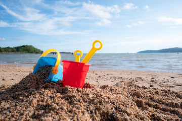 Toy against scenic of summer sand beach and cloudy blue sky