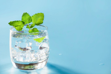 Glass of water with mint on pastel blue. One shot for time. Close up. Water balance for healthy.