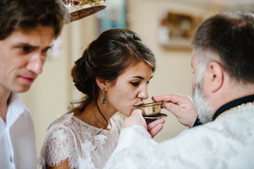 The priest blesses and gives in the cup the blood of God, wine for the bride and groom. Newlyweds,...