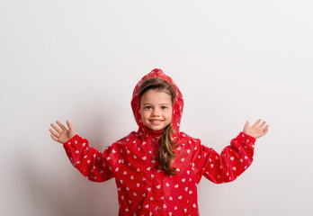 Portrait of a small girl with red anorak in studio on a white background. © Halfpoint