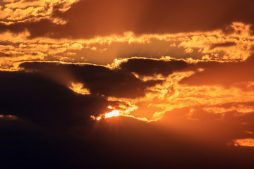 Dramatic sky with dark clouds and orange sun at sunset