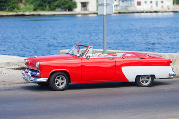 Vintage, classic, red American car parked at Havana City in Cuba. Old cars very popular transportation for tourist.