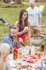 Happy group of friends having a grill party by a table full of food.