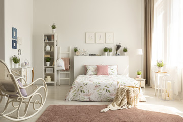 White bedroom interior with dirty pink carpet, rocking chair, window with drapes and king-size bed...