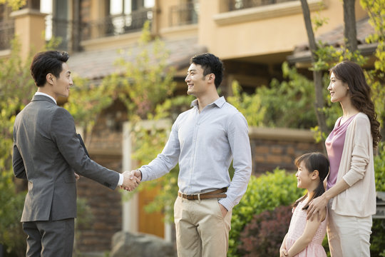 Happy young family shaking hands with realtor