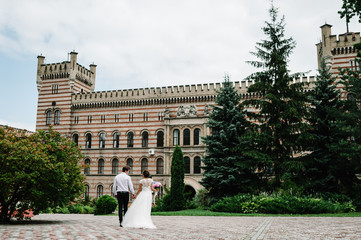 Obraz premium Newlyweds go back to the ancient restored architecture, old building, old house outside, vintage palace outdoor.