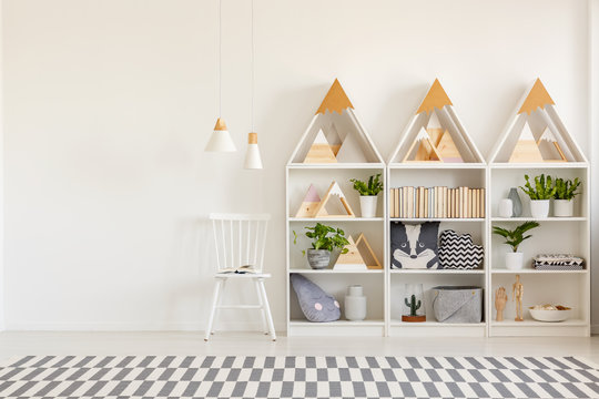 Lamps above white chair above the wall with copy space in scandi kid's room interior. Real photo