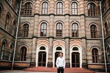 Fototapeta na wymiar Handsome portrait groom, man stand on old stone pavement near vintage palace outdoor, old building.