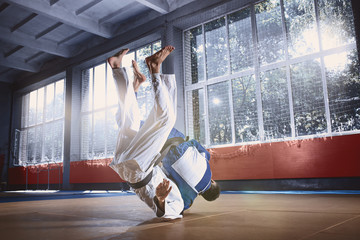 Two judo fighters showing technical skill while practicing martial arts in a fight club. The two fit men in uniform. fight, karate, training, arts, athlete, competition concept