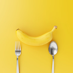 Banana with fork and spoon on yellow background. minimal food concept.