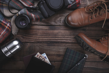 Traveler's photographer's accessories camera lense boots thermos purse with money plaid and notepad on old barn wood background