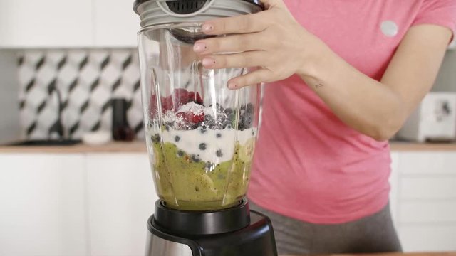 Woman putting the ingredients in the blender and mixing them