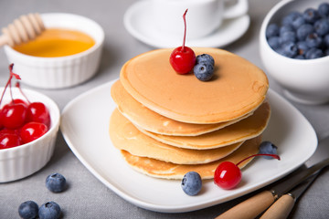 Pancakes with blueberries, cherries and honey. Close-up. Selective focus.