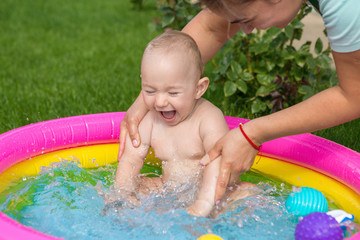 A small child is bathing in a pool, inflatable children's inflatable pool in summer	