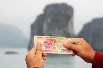 A Vietnamese note of two hundred thousand dong shot against the limestone in Ha Long Bay that is...