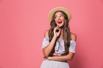 Portrait of pretty glamour woman 20s wearing straw hat laughing and looking aside, isolated over pink background in studio