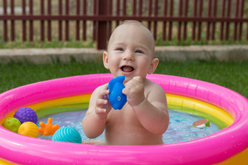 A small child is bathing in a pool, inflatable children's inflatable pool in summer