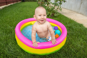 A small child is bathing in a pool, inflatable children's inflatable pool in summer