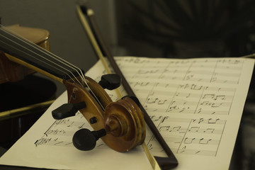Obraz na płótnie Canvas violin arm, bow and hand written music sheet over black grand piano
