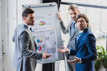 high angle view of businessman standing near whiteboard with business charts and discussing project