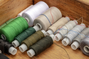Fototapeta na wymiar A closeup photo of sewing thread spools, beige and brown, in a wooden box