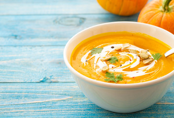 Pumpkin and carrot soup with parsley on blue background Top view.