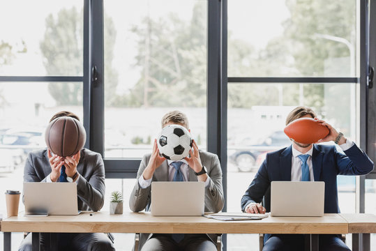 young office workers holding balls while working with laptops in office