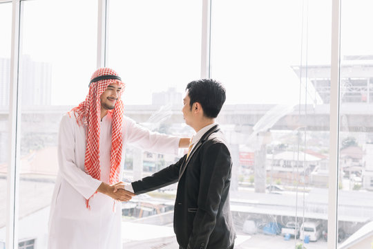 Arab Business Partners with Asian Partners After a successful business deal.Two businessman shake hand as a greeting.