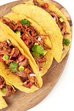 Overhead closeup photo of Mexican tacos with pulled pork, avocado, chili peppers, cilantro, with place for text, on white