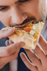 cropped shot of young businessman eating pizza