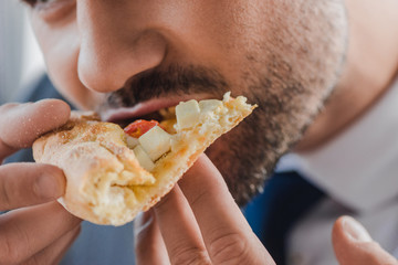 close-up view of young businessman eating pizza