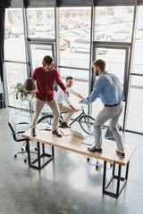 high angle view of young businessmen having fun with basketball ball at workplace