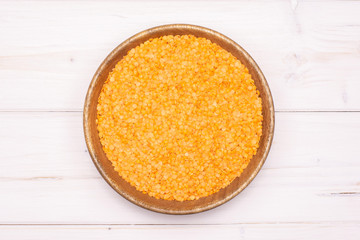 Lot of whole raw red lentils with wooden bowl flatlay on grey wood