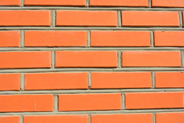 Beautiful masonry of red bricks, a wall of building bricks and gray cement in the sun