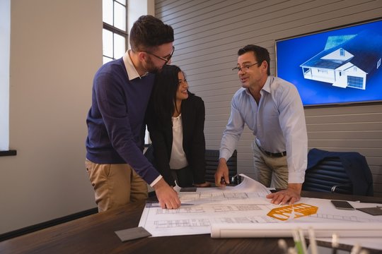 Business colleagues discussing over blueprint in meeting room