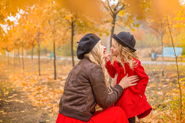 beautiful mother and daughter on a background of autumn garden gently embrace each other